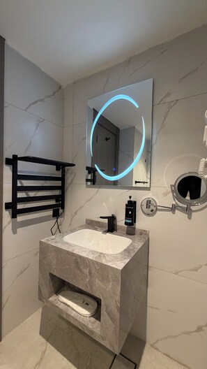 A modern bathroom with a marble sink, a black towel rack, a mirror with a blue light, and a round mirror on the wall. - 102 tara-JRE Al Lweibdeh 2BDR duplex apartment (Amman)