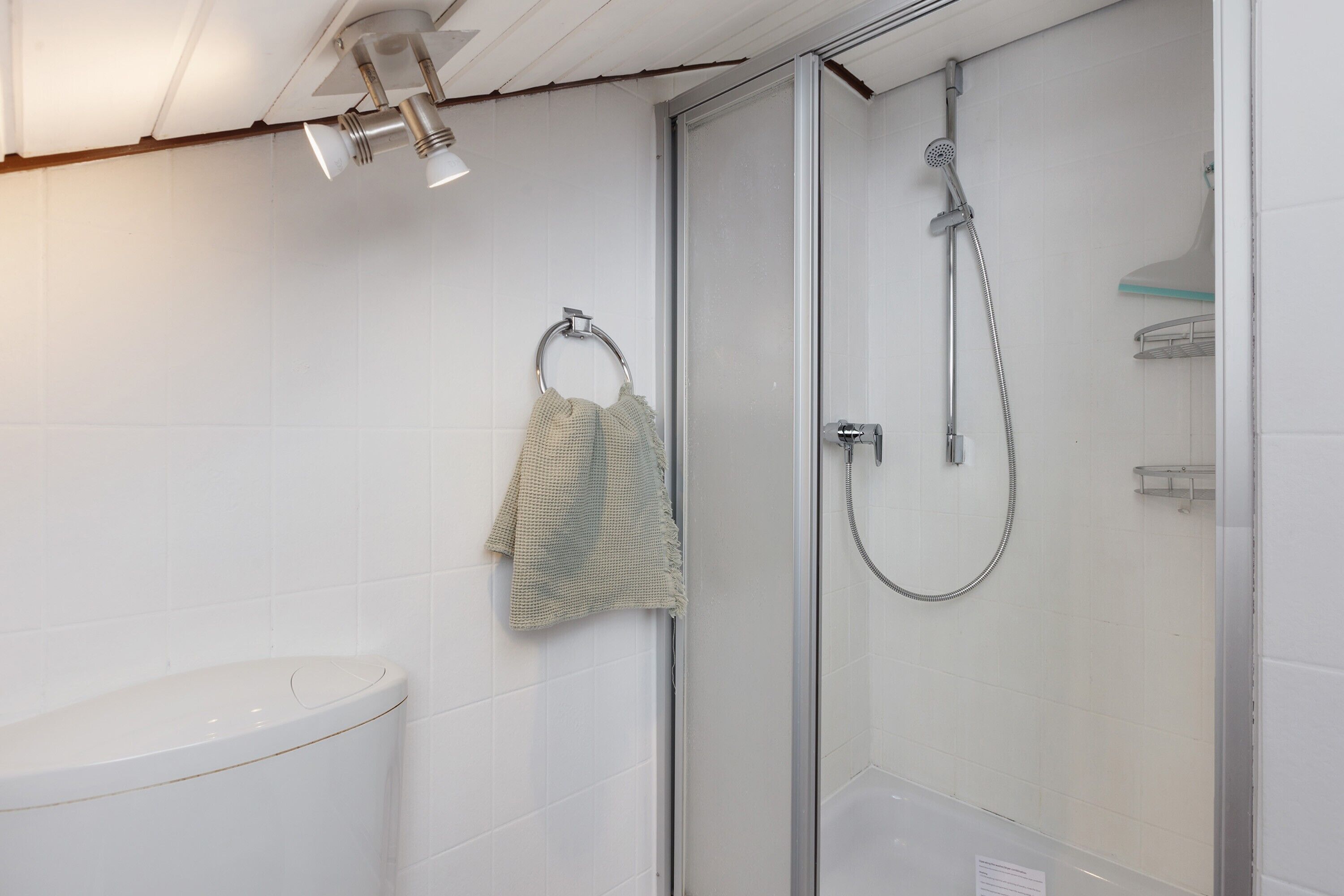 Ein Badezimmer mit Toilette, einer Glasdusche und einem Handtuch an einem Metallring.