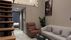 A modern living room with a sofa, a coffee table, a chair, and a staircase. - 103 tara-JRE Al Lweibdeh 2BDR duplex apartment (Amman)