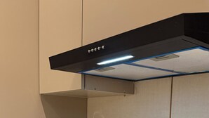 Una cocina con placa de inducción, cafetera, botellas de agua y lavavajillas.