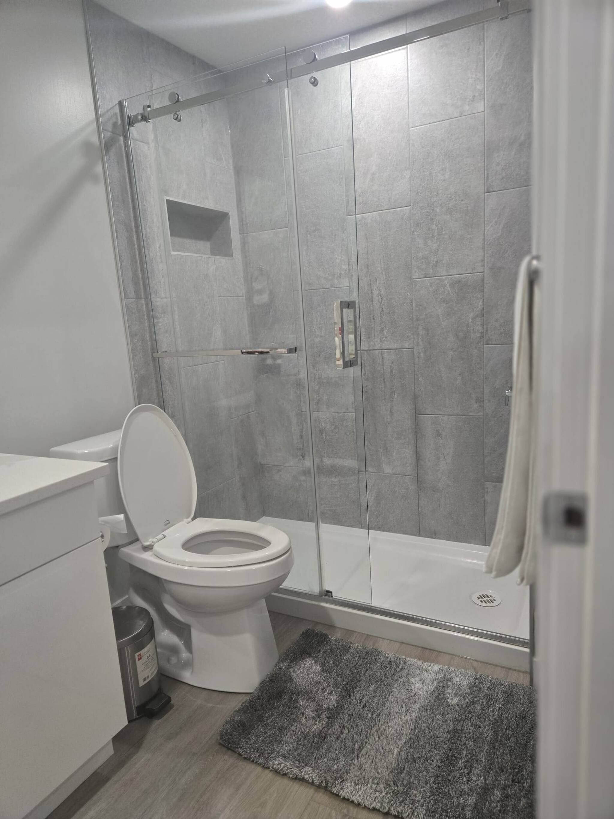 A bathroom with a toilet, a shower enclosure, and a towel rack.