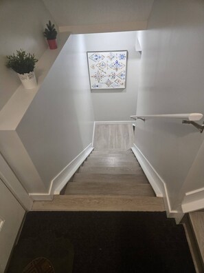 Eine Treppe mit Handlauf, Wandverkleidung mit Muster und Topfpflanzen.