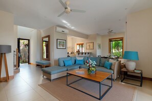 A living room with a sectional sofa, a coffee table, a lamp, and a ceiling fan. - Attractive 3-Bedroom Villa / Infinity Pool & Terrace (Bel Ombre)