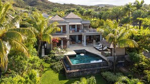 A large house with a swimming pool surrounded by lush greenery and palm trees. - Attractive 3-Bedroom Villa / Infinity Pool & Terrace (Bel Ombre)