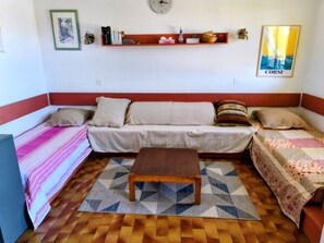 Una habitación con un sofá, una mesa de centro de madera, un tapete estampado y un reloj de pared.