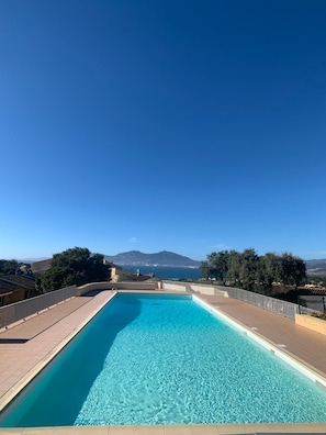 Piscina azul cristalina con vistas a montañas y un cielo despejado.