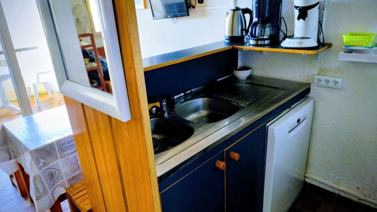 A compact kitchen with a sink, a coffee maker, and a dishwasher.