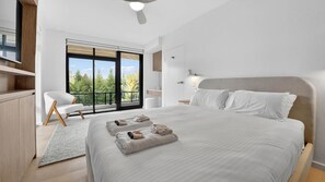 A modern bedroom with a large bed, a seating area with a chair, and a balcony with a view of trees. - Spacious North Bondi Apt w Balcony near beach (North Bondi)