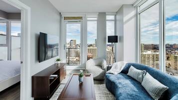A modern living room with a large window, a sofa, a coffee table, and a TV.