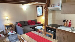 Zona d'estar acollidora amb taula de dinar, sofà i cuina.