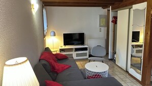 Un saló amb un sofà, televisió, làmpada i una taula petita.
