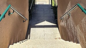Una escala coberta que condueix a l'entrada d'un edifici, amb vista a una zona residencial.