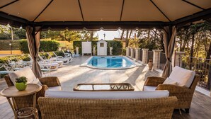 Un espacio al aire libre cubierto con una piscina, mobiliario de mimbre y un cobertizo pequeño.