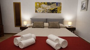 Una habitación de hotel con una cama grande, dos mesitas de noche, un cuadro sobre la cama y toallas sobre la cama.