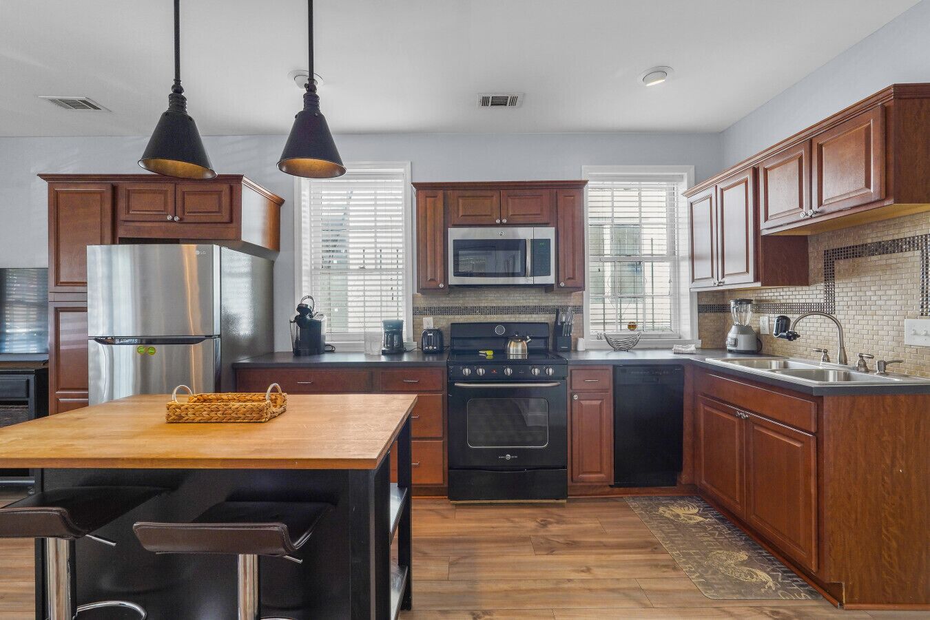 A modern kitchen with wooden cabinets, stainless steel appliances, and pendant lighting.