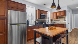 A modern kitchen with wooden cabinets, stainless steel appliances, and a central island. - Lower Carriage House at Wayne Mansion Estate (Savannah)