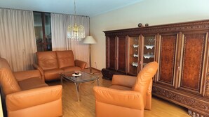 Un salon avec des canapés en cuir, une table basse en verre, un lampadaire et un meuble en bois doté de portes en verre.