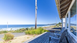 A wooden deck with chairs overlooking a coastal view.