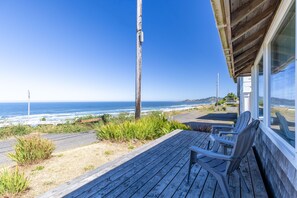 A wooden deck with chairs overlooking a coastal view.
