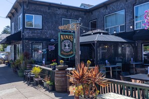 A building with a sign reading 'NANA'S IRISH PUB' and outdoor seating with potted plants. - Lighthouse Lookout at Nye Beach * Ocean View (Newport)