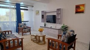 Sala de estar con televisor, sofá y comedor.