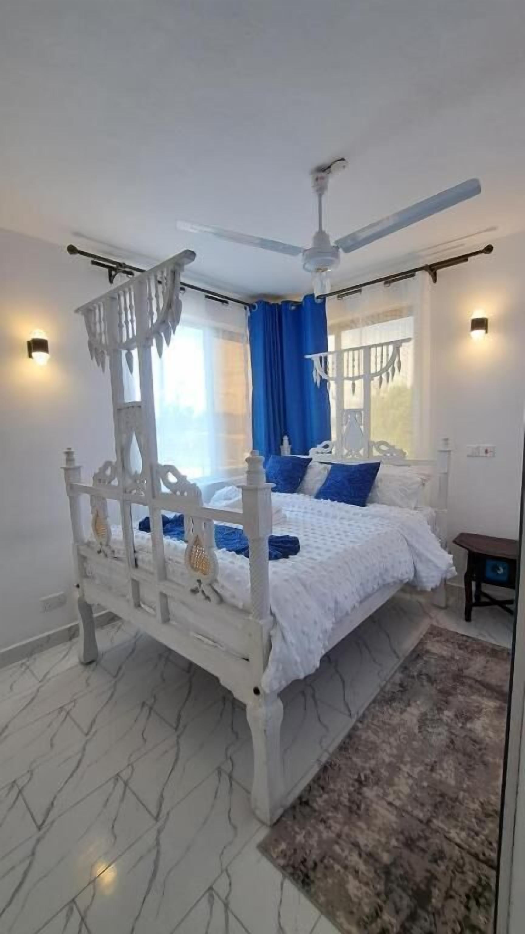Un dormitorio con cama con dosel, ventilador de techo y mesita de noche.
