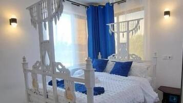 Un dormitorio con cama con dosel, ventilador de techo y mesita de noche.