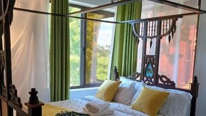 Una cama con dosel, cortinas verdes y vistas al exterior.