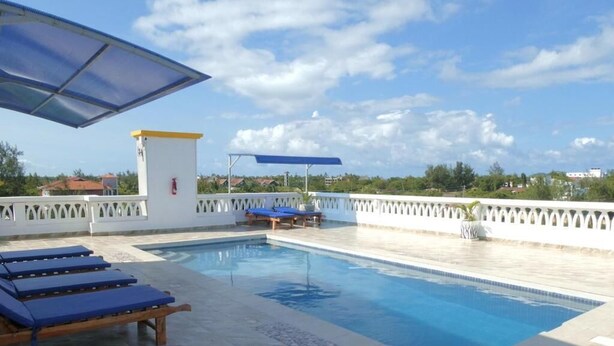 Piscina con sillones de descanso, torre de salvavidas y cielo despejado.