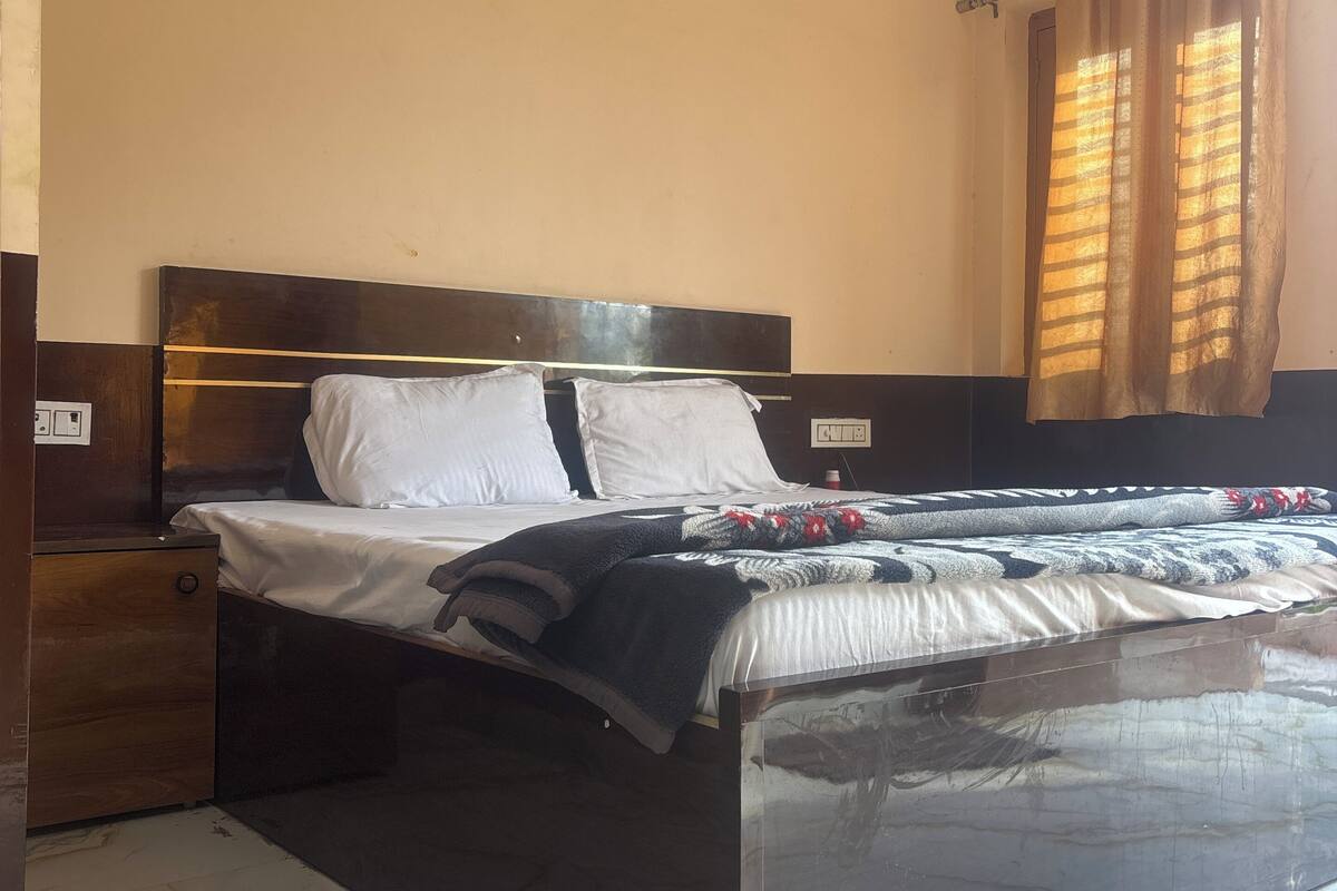 Un dormitorio con cama, mesita de noche de madera, suelo de mármol y equipo de aire acondicionado.