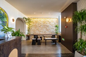 A reception area with a stone wall, a reception desk, several benches, and potted plants. - Bay Four Seasons Castle Hotel (Weihai)