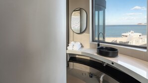 A modern bathroom with a large window, a round mirror, and a sink with a black basin. - Bay Four Seasons Castle Hotel (Weihai)