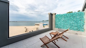 A balcony with a view of the beach, a wooden chair, and a small table. - Bay Four Seasons Castle Hotel (Weihai)