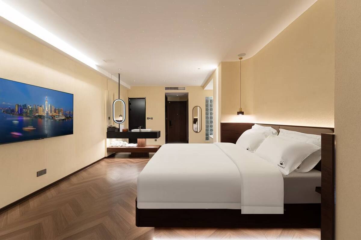 A hotel room with a bed, a TV, a bathroom, and a cityscape view.