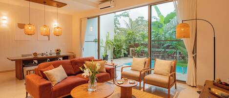 A modern living room with a sofa, armchairs, a coffee table, and a dining area with a table and chairs.