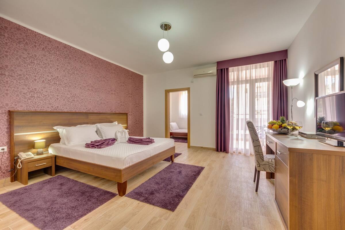 A bedroom with a bed, bedside table, lamp, and a desk with a chair.