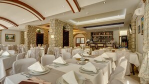 A restaurant with tables set for dining, a bar area, and a stone wall.