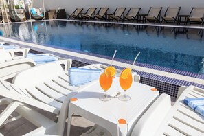 A poolside area with lounge chairs and a table with two drinks. - Akapulco Hotel (Sutomore)