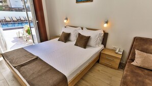 A bedroom with a bed, wooden nightstand, and a view of a pool.