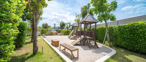 A playground with a wooden play structure, a bench, and a sandbox.