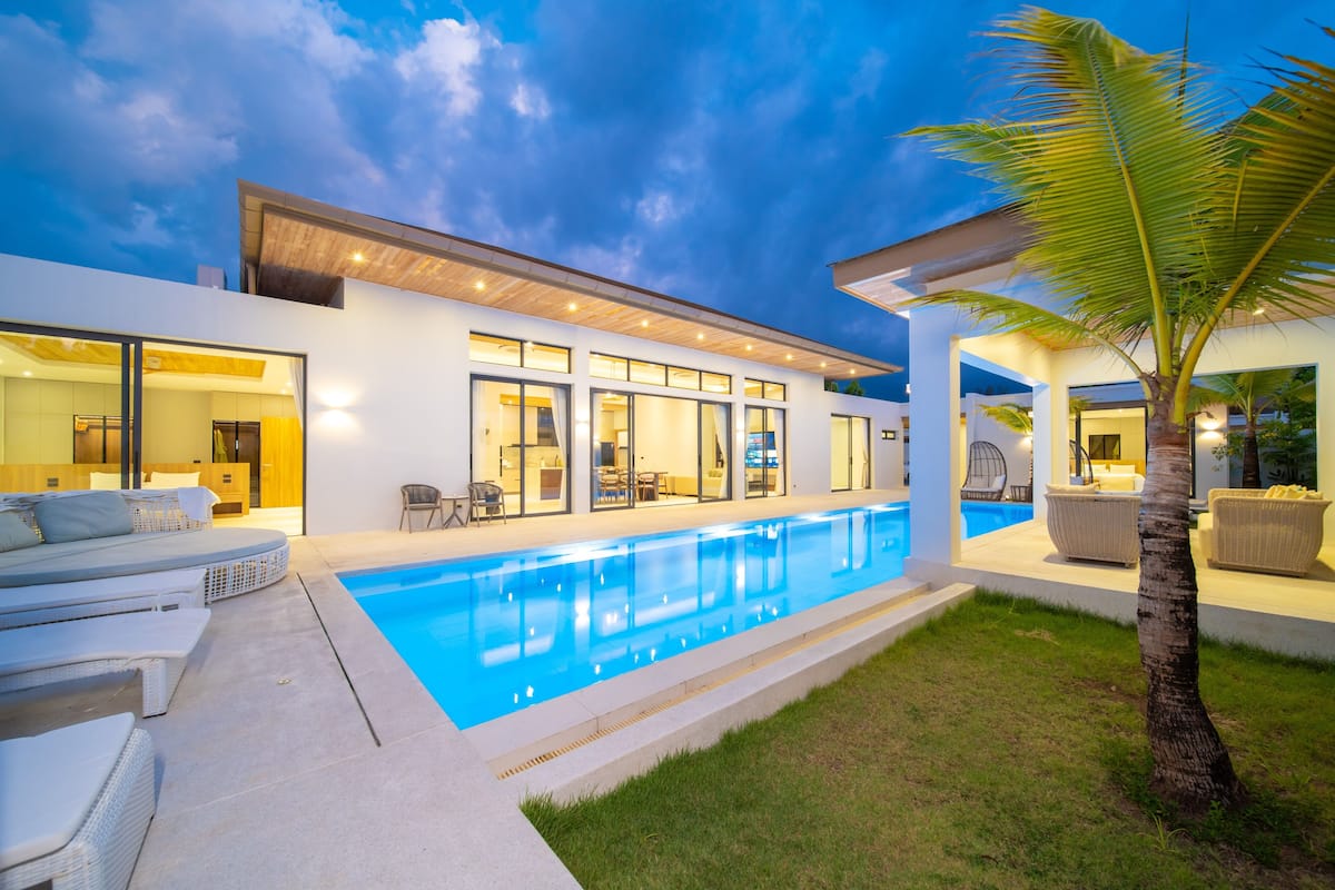Ein modernes Haus mit Schwimmbad, Außenbereich zum Sitzen und einem gut beleuchteten Innenraum.