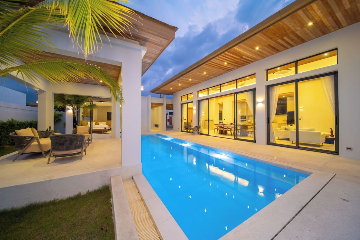 Ein modernes Haus mit Schwimmbad, Sitzgelegenheit im Freien und großen Fenstern.