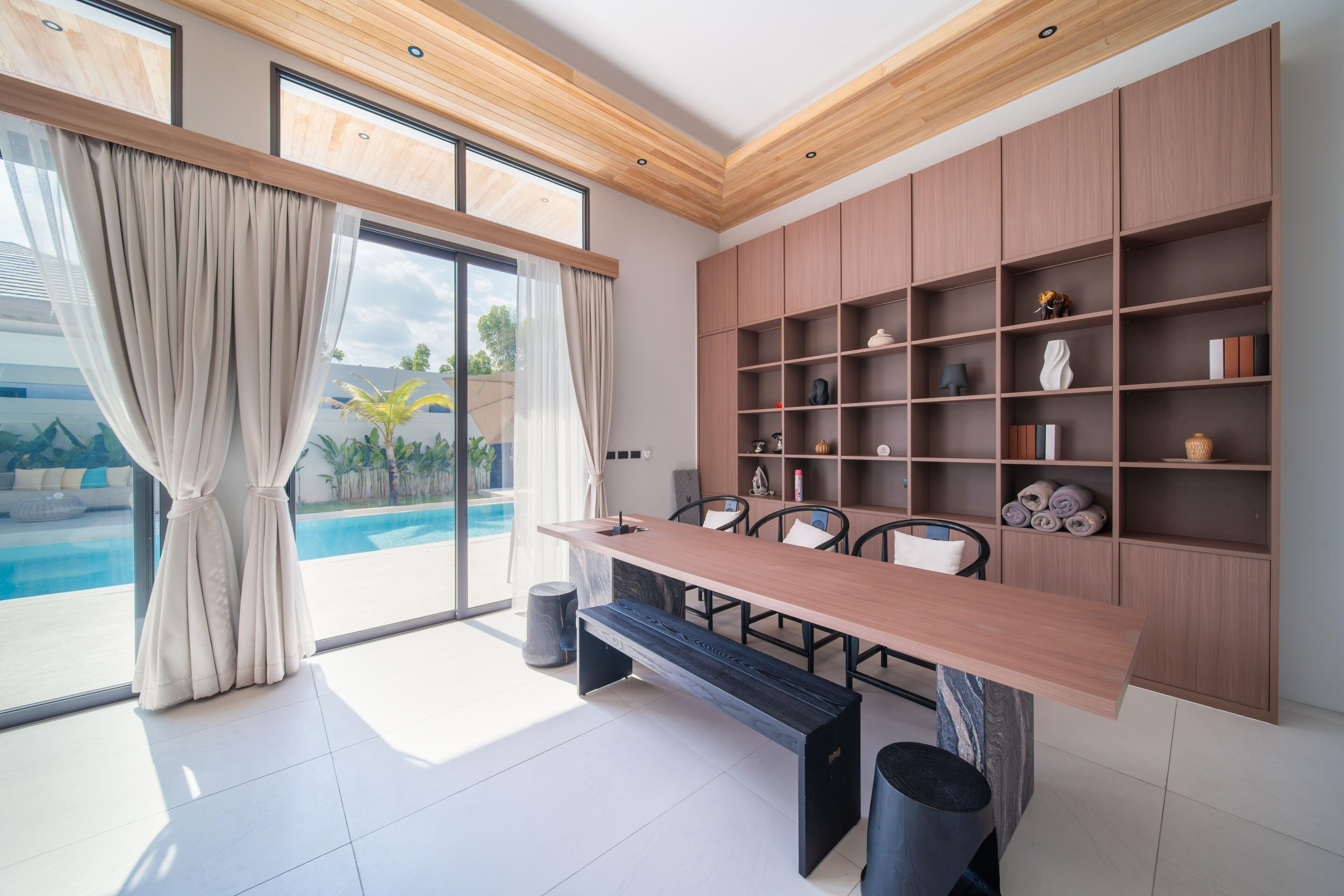 Un espace repas moderne avec une longue table, des chaises et une bibliothèque intégrée en bois.