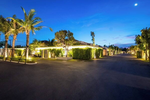 A well-lit street with palm trees, a building with illuminated windows, and a clear night sky.