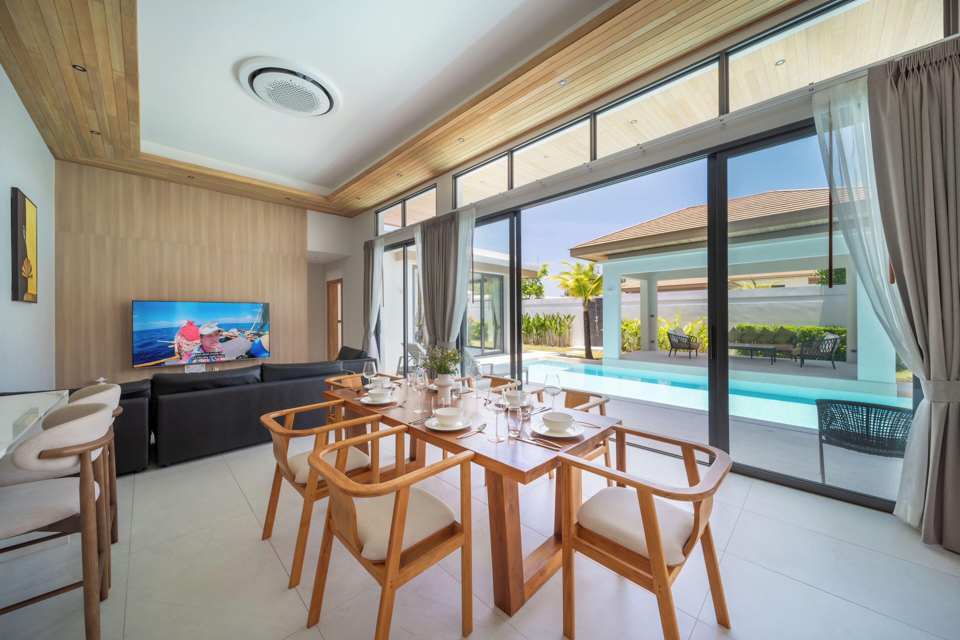 Una sala moderna con comedor, ventanas amplias y vista a la piscina.