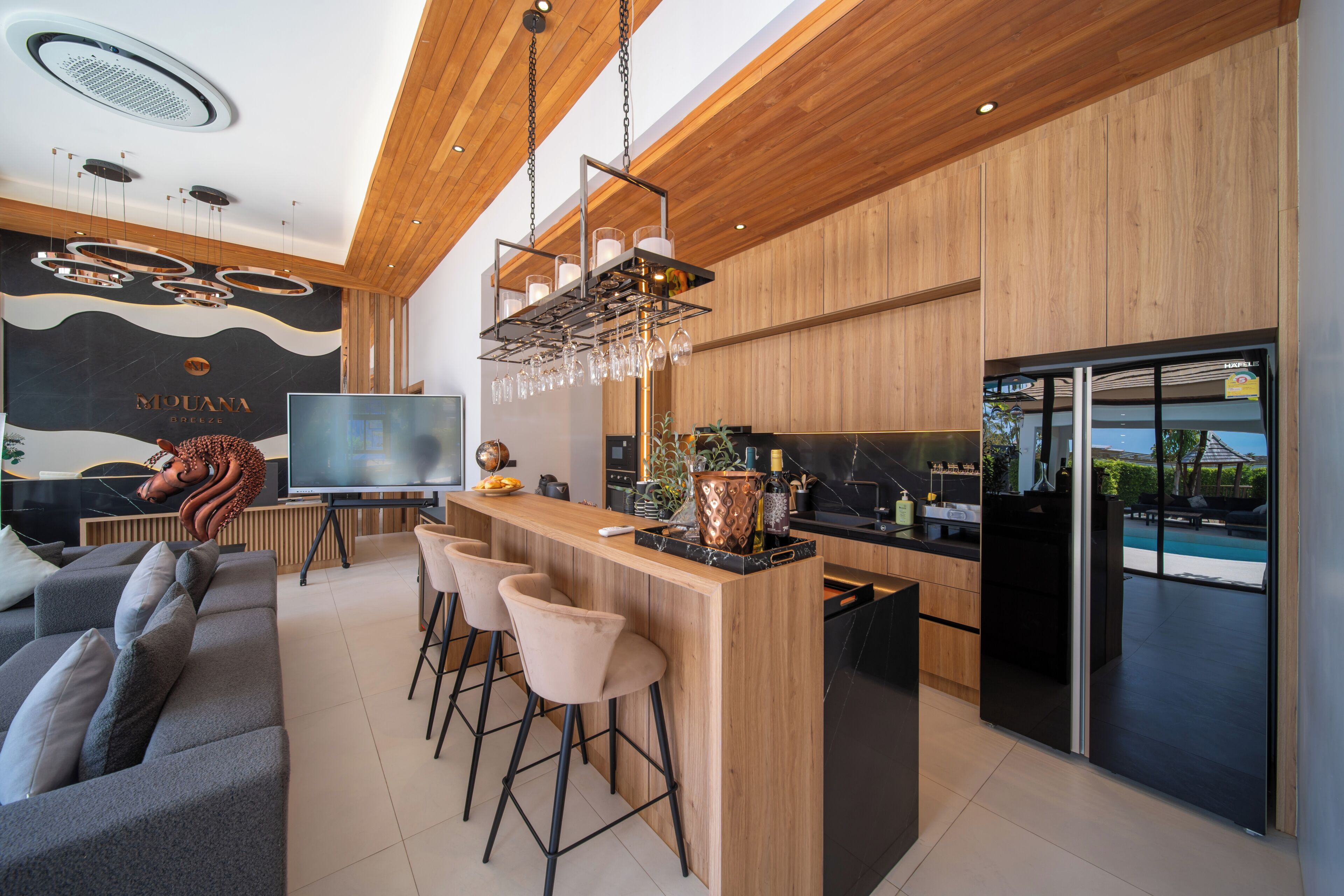 Una cocina moderna con barra, techo de madera y un televisor grande.