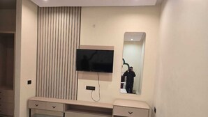 A modern bathroom with a vanity, a mirror, and a television mounted on the wall. - Hotel Shravan Royal Inn  (Jaipur)