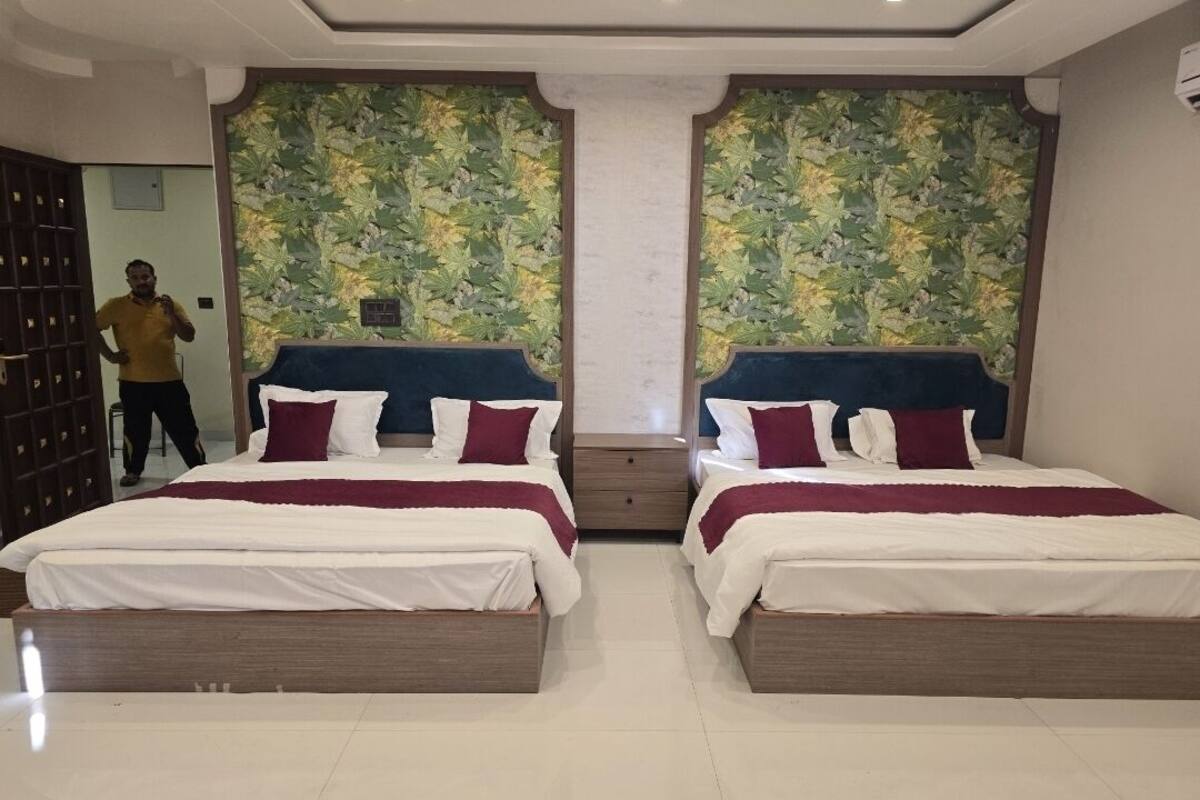A hotel room with two beds, a large mirror, and a decorative wall.