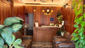 A reception area with a wooden reception desk, leather sofas, potted plants, a chandelier, and a marble-patterned floor. - WHITE FORT THEKKADY (Kumily)