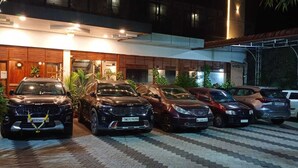 A hotel with a modern facade, a parking area with multiple cars, and a well-maintained garden. - WHITE FORT THEKKADY (Kumily)